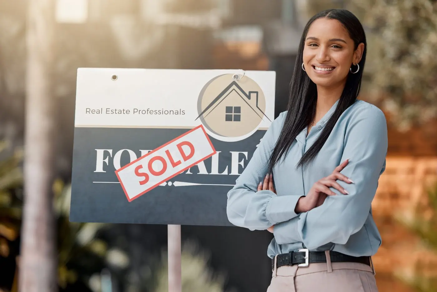 Real estate agent beside a sold sign